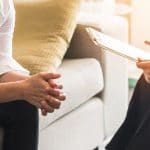 Doctor or psychiatrist talking to their client. Speaking to your ideal clients and listening to the words they use or reviewing intake paperwork is a great way to begin your keyword research.