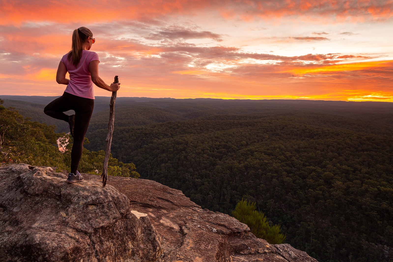Image of a woman standing on one foot holding a stick on the top of a cliff overlooking the sunset. With comprehensive SEO services for therapists and counselors, you can focus on what you do best as a private practice owner. Get SEO help for therapists with Simplified SEO Consulting.