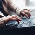 A photo captures an individual typing on a laptop. They are signing up for a free consultation with Simplified SEO Consulting. They are excited to begin their Done For You Services.