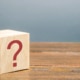 Image of a wooden block with a red question mark on its side. This image illustrates the many questions clients have about SEO, including "how long does SEO take?"