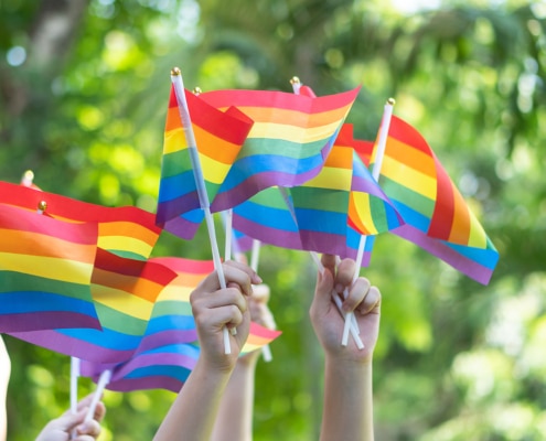 An image of multiple hands holding up pride flags. This image represents how an SEO specialist for therapists can help someone searching "SEO for therapists" to make their website more inclusive.