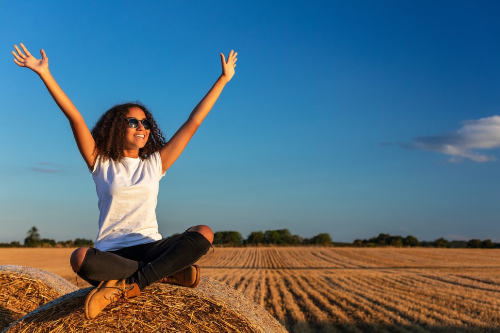 Happy woman in a field raising her hands up. She taught herself the basics of SEO for therapists to optimize her therapist website or therapy website for search engines.