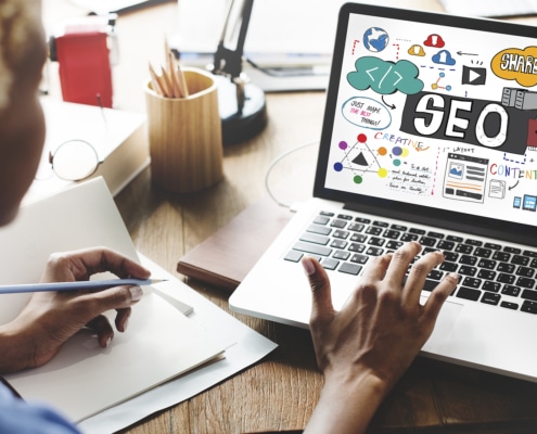 A close-up of a woman typing with an SEO graphic on her laptop. This represents support for local SEO for therapists. Contact Simplified SEO Consulting to learn more about how we can support your private practice website today!