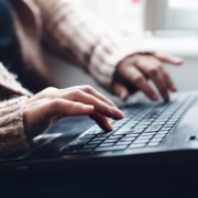 woman in a sweater types on a laptop representing blogging for SEO. Learn more from an seo expert and copywriter at Simplified SEO Consulting