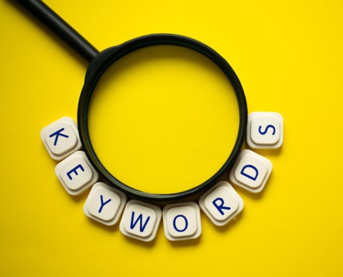 Photo of a magnifying glass with the word keyword spelled out underneath representing how mental health keywords can be used through blogging to improve SEO for therapists and counselors