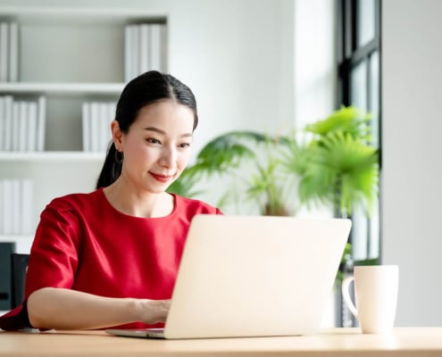 Photo of a woman using a computer at her desk representing the way therapists and counselors can add keywords to a counseling website through blogging to boost their SEO