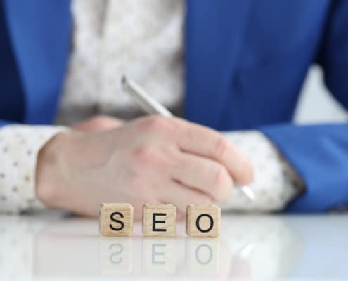 Image of SEO spelled out in blocks in front of someone wearing a suit. Simplified SEO Consulting specializes in mental health SEO. We give specialized and tailored search engine optimization for counselors. A part of this includes footer SEO. Call today to get a consultation.