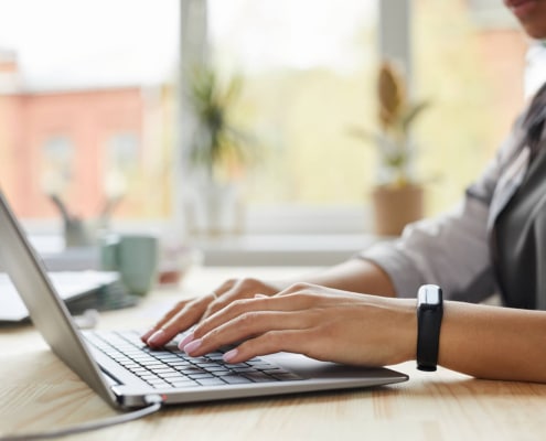 Photo of a woman typing on a computer representing the way therapists can use blogs and counseling service pages to improve their SEO and rank better on Google.