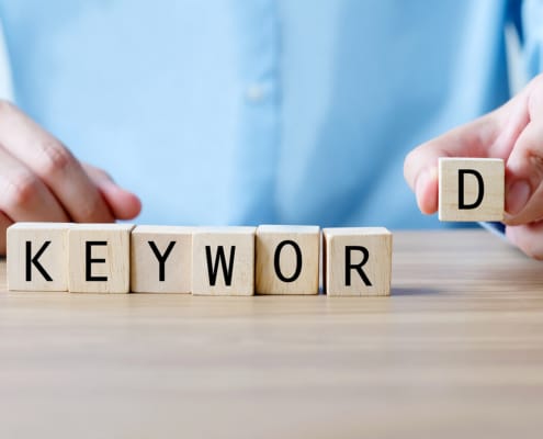 Photo of a man putting the word keyword together with lettered blocks. This photo represents the importance of using SEO keywords for personal injury lawyers to rank higher on Google. Contact us today to learn more.