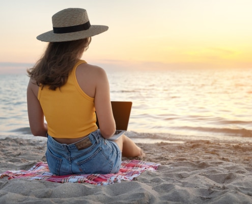 Woman blogging on the beach during a Carnival Liberty cruise for SEO cruise to learn how to do blogging for therapists in Florida and throughout the United States.