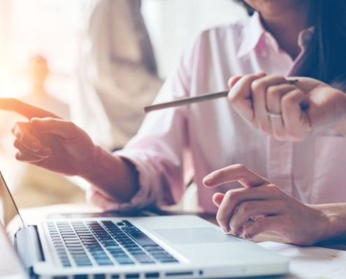 Shows two people looking at a laptop. Represents how making website mistakes can affect your private practice's SEO