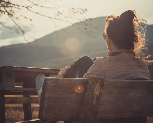 Photo of a young woman sitting outside at a park. This represents how writing local blogs about locations can boost your practice's SEO.