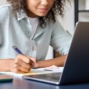 Woman looking at her computer and writing things down. Representing how SEO for therapists can help during Covid-19