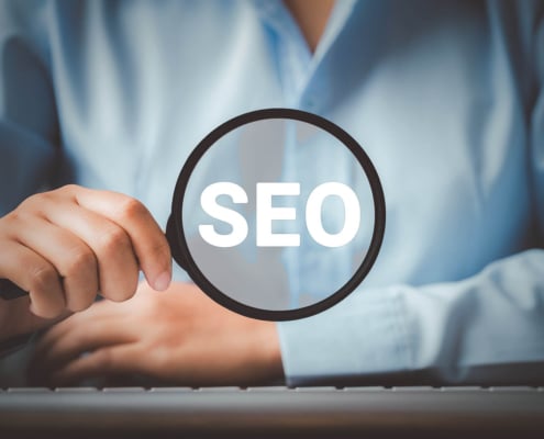 Woman holding a magnifying glass displaying the words SEO. Represents how personal injury lawyers can use SEO to reach their ideal clients. Start today.