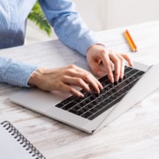 Shows a therapist typing a blog on their laptop. Represents how therapists show write their own blogs to avoid duplicate content in pre-written therapist content.