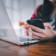 Photo of a woman using her laptop and cell phone with a search bar over the image. This photo represents the simple way of incorporating internal links into your service pages.