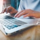 A person types on a laptop while sitting at a table. Want to learn what SEO strategy in the healthcare industry can do for your business? Our team specializes in healthcare SEO and can help you!