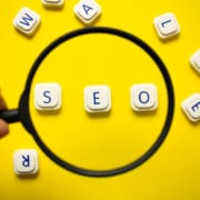 A hand holds a magnifying glass over the words SEO. Having trouble understanding SEO in healthcare? Our team of specialists can help you understand healthcare SEO and how to implement it.