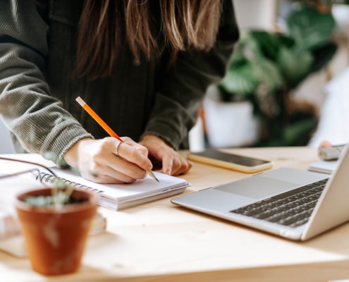 Shows an SEO copywriter taking notes. Represents how a copywriter can benefit seo coaching by supervising ChatGPT and the content it produces.