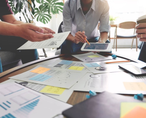 A group of people around a table talk with their hands and have papers laying on the table. Looking for SEO examples in healthcare to better understand it? Our team can help you grasp the concept of healthcare SEO and how to use it.