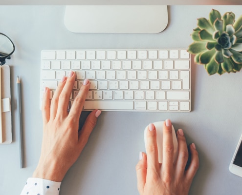 Photo of a woman using her mouse and keyboard to check on her page speed for her website. By checking your page speed you can determine how long it takes for your web page to load.