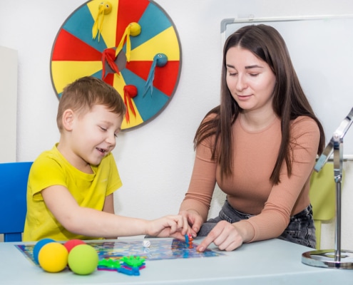 Photo of an SLP providing speech therapy to a young boy. This represents games they might play and a photo an SLP might include on their private practice website. For SEO purposes, it's important to condense photos like I did with this one and choose photos that represent the thing you are discussing such as how this one represents a photo an SLP might actually use on their website and is placed in the blog post where I'm discussing photo optimization for SEO.