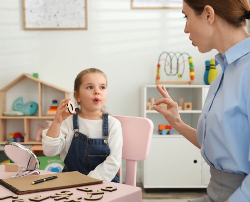 Photo of a private practice speech therapist helping a little girl.