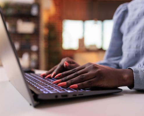 Photo from Bigstock of an African American female's hands on a computer representing a private practice owner who wants their speech therapy practice to rank well on Google and improve their SEO without blogging.