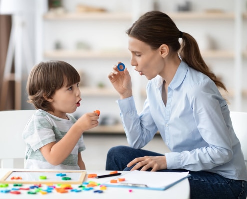 Photo of a speech pathologist working with a young boy on articulation. This represents a pediatric SLP with a full private practice able to see the clients she works most effectively with.