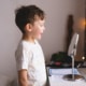 Photo of small boy looking at mirror representing a boy who's pediatric speech therapist has done excellent keyword research and used both long tail keywords and short tail keywords as part of their overall SEO strategy.