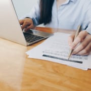 A woman writes on a paper while working on a laptop. Want to learn more about SEO in healthcare? Our services can help you incorporate healthcare SEO into your website.