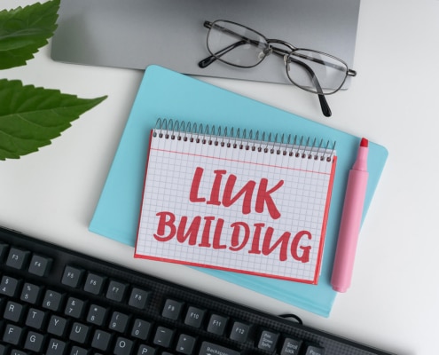 A top down view of a notebook in front of a laptop that reads “link building”. Learn how to build links to improve SEO for therapists by building backlinks for therapists. Find a guide to earning backlinks to learn more today.