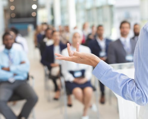 A person speaks in front of a group of business professionals. Want to see how SEO for private practice makes a difference? Speak with our team to learn more ways to do it.