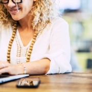 Smiling woman wearing white working on laptop. Learn to work on your private practice SEO with the help of Simplified SEO Consulting.