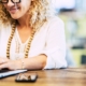 Smiling woman wearing white working on laptop. Learn to work on your private practice SEO with the help of Simplified SEO Consulting.