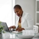 Shows a black, woman therapist taking notes with a pen and notepad while looking focused. Represents how you can not use copywriting ai tools and still implement private practice SEO.