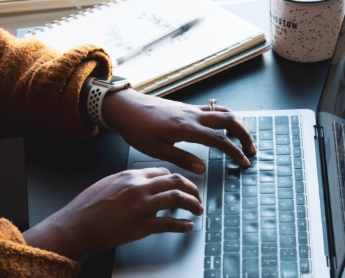 Shows a pair of black hands typing on their laptop to implement therapist SEO. Represents how counselor seo can be enhanced with AI assisted writing.
