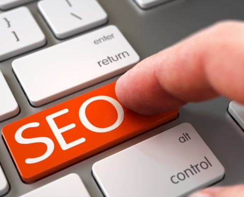 Finger pushing SEO orange laptop keyboard key. Discover how you can begin finding your ideal clients with the help of SEO.