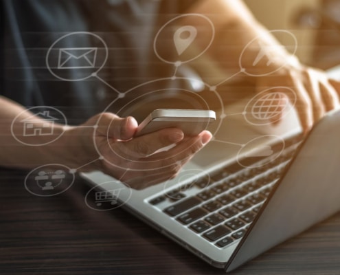 Image of someone typing on a laptop and holding a cell phone. If you want your website to begin ranking on search engines, find support with Simplified SEO Consulting to find SEO help for therapists.