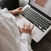 Shows a therapist working on her counselor SEO by typing up a blog on her silver MacBook. Represents how SEO marketing for counselors helps therapists reach their ideal clients.