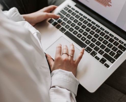 Shows a therapist working on her counselor SEO by typing up a blog on her silver MacBook. Represents how SEO marketing for counselors helps therapists reach their ideal clients.