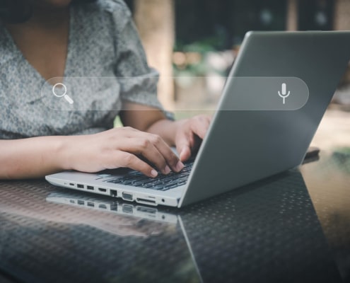 An individual typing on a laptop with a search bar appearing. Discover how keyword research is changing in the SEO world by reading our blog. We can help you boost your online presence today!